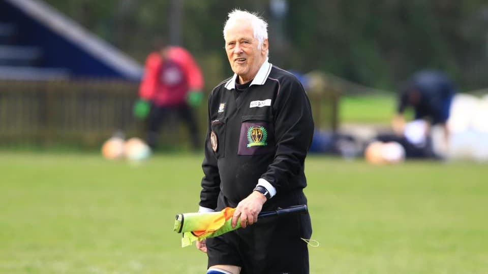 A Chester referee carrying an assistant referee flag on a football pitch